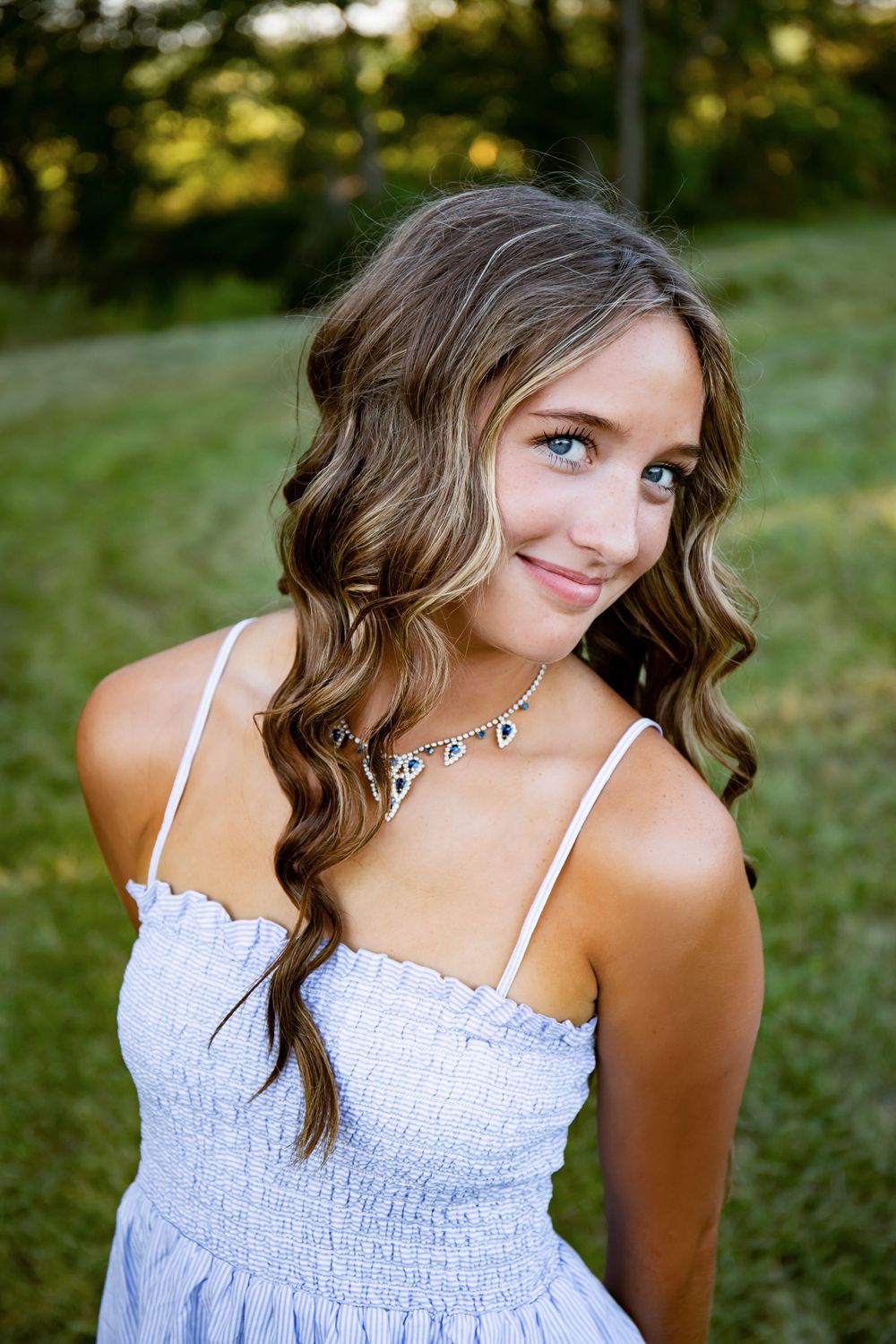 Outdoor portrait featuring a white summer dress and delicate crystal necklace.