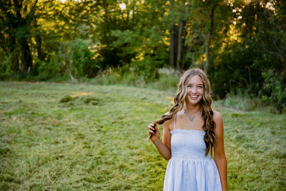 A joyful outdoor portrait captured in a sunlit field with trees in the background.