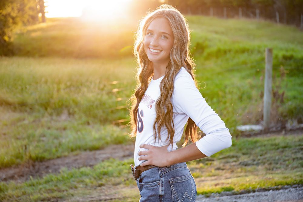 Sunset portrait wearing a white cardigan and jeans in warm golden light.