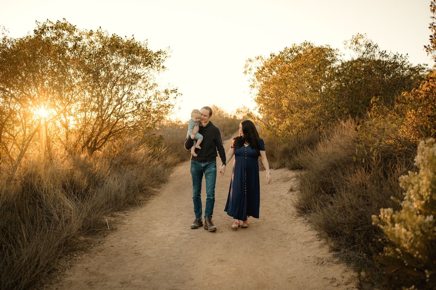 Family portrait by Poway Photographer, of family walking along sunlit path in San Diego with their little boy