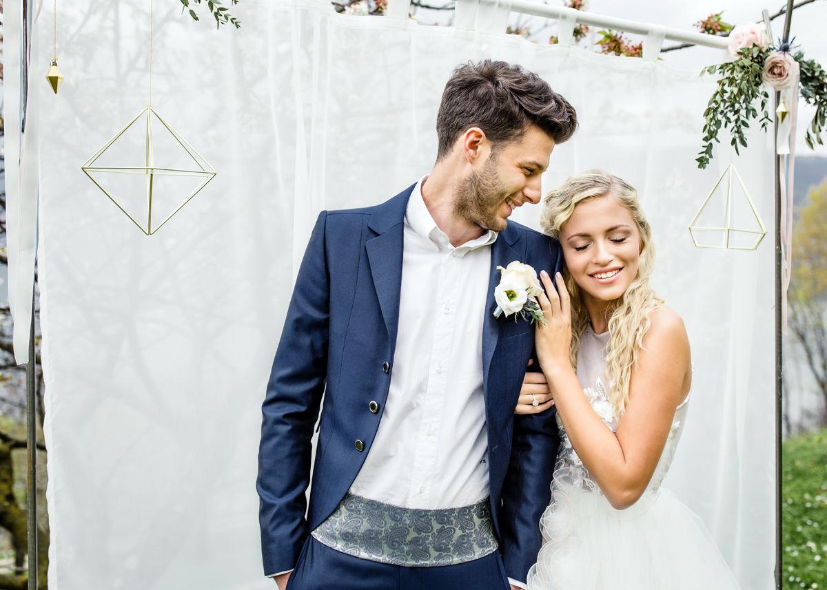 Groom in a navy blue suit and bride in a lace wedding dress posing together for a photo shoot in Italy.