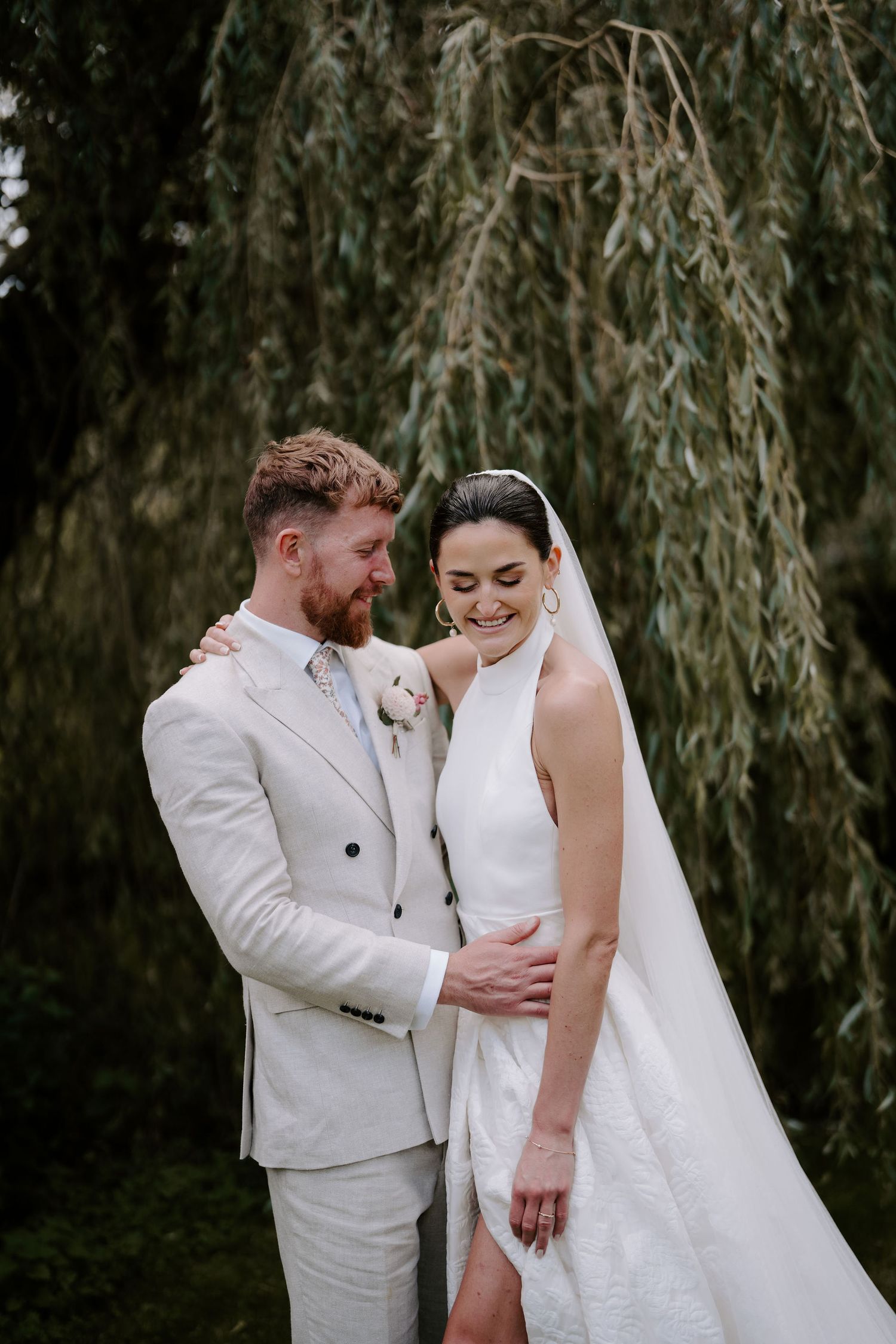 bride and groom smiling under willow tree in islip, oxfordshire