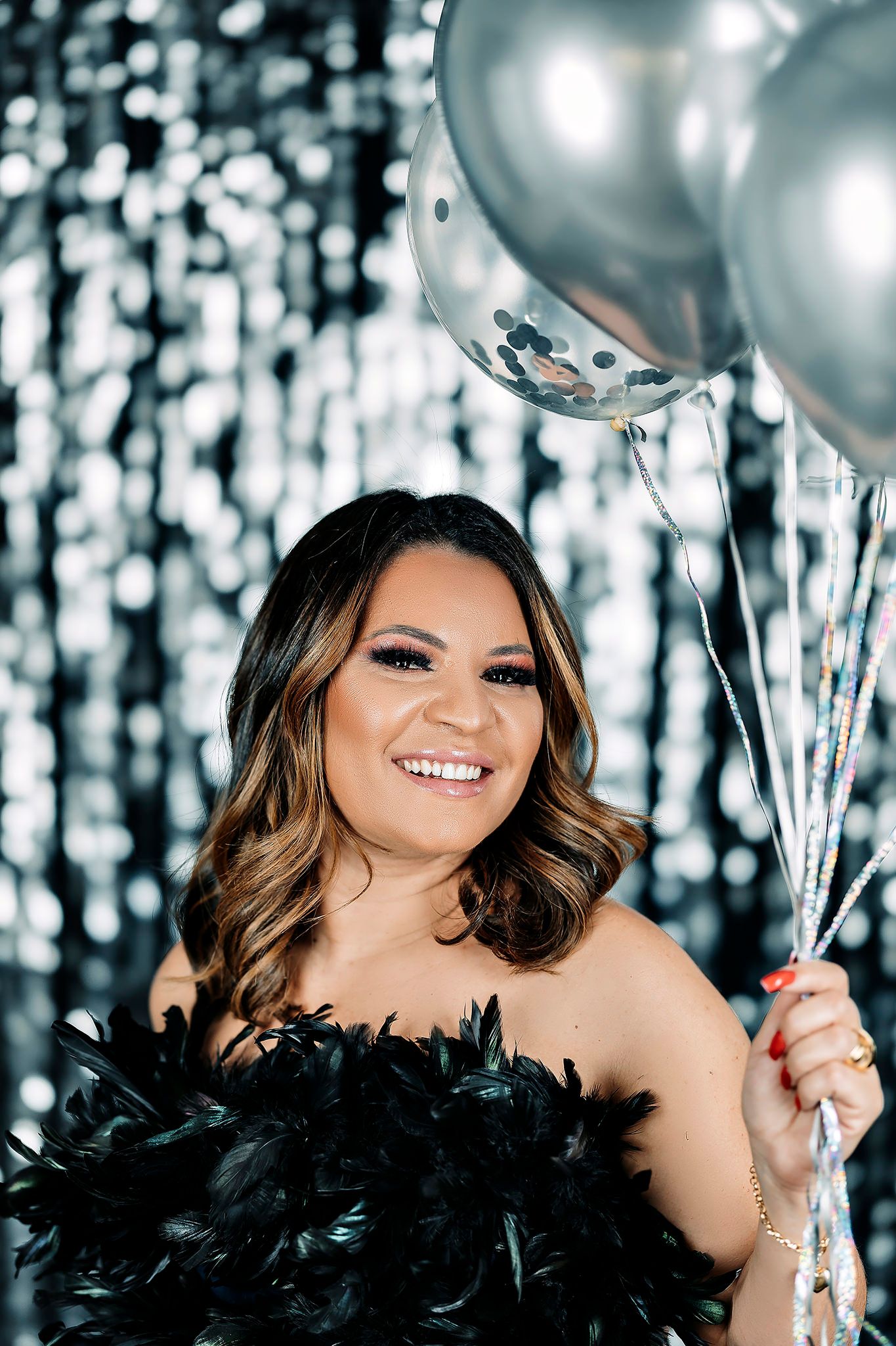 Festive portrait session with feathered dress detail and silver balloons.