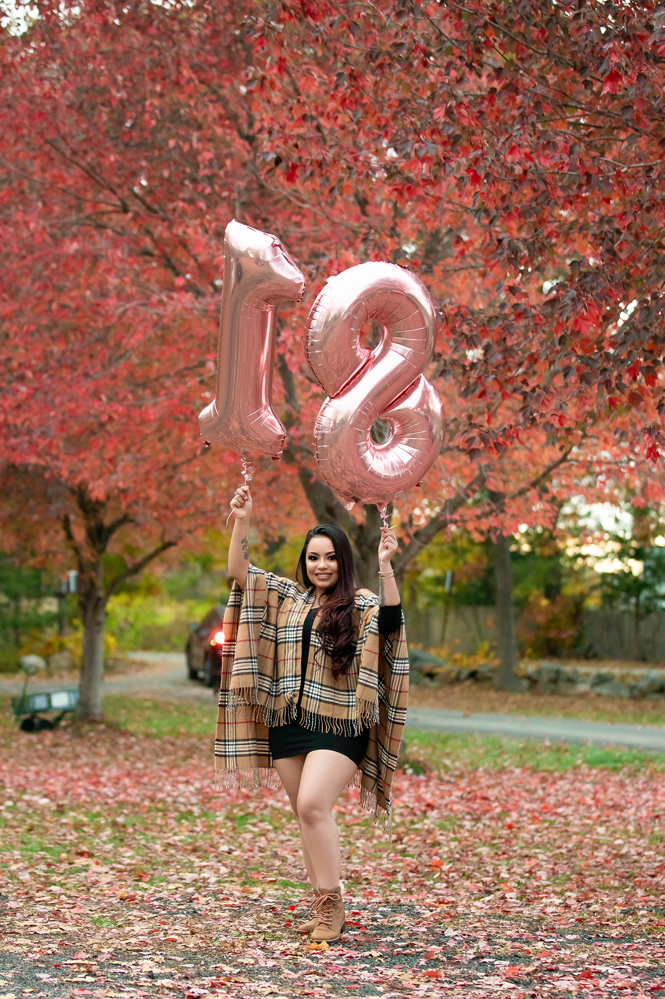 Pink heart balloons float among red autumn leaves during an outdoor photo session.
