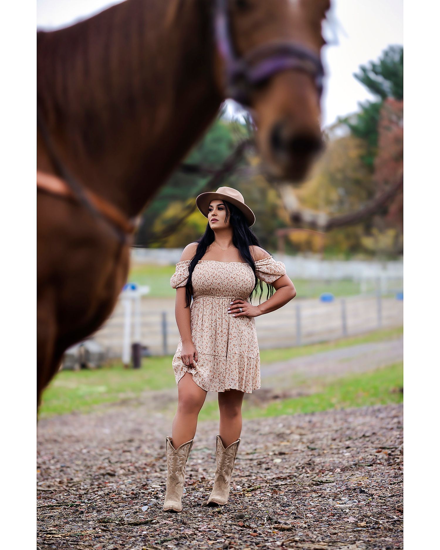 Country style photoshoot near barn featuring floral dress and boots.