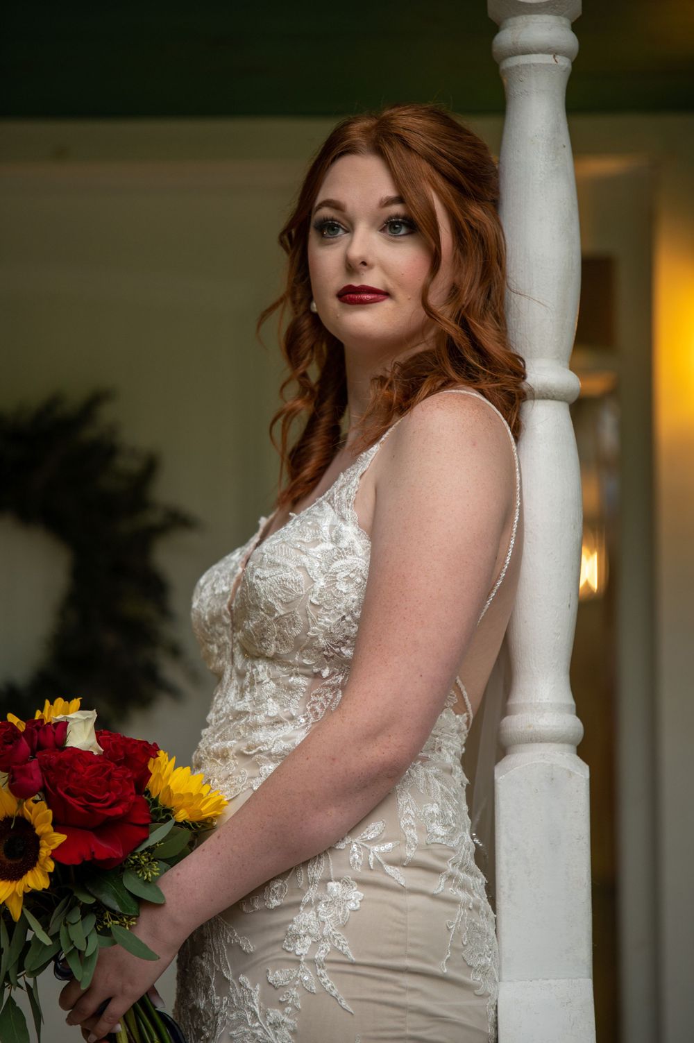 Elegant lace wedding dress being worn in a portrait setting near a white column.
