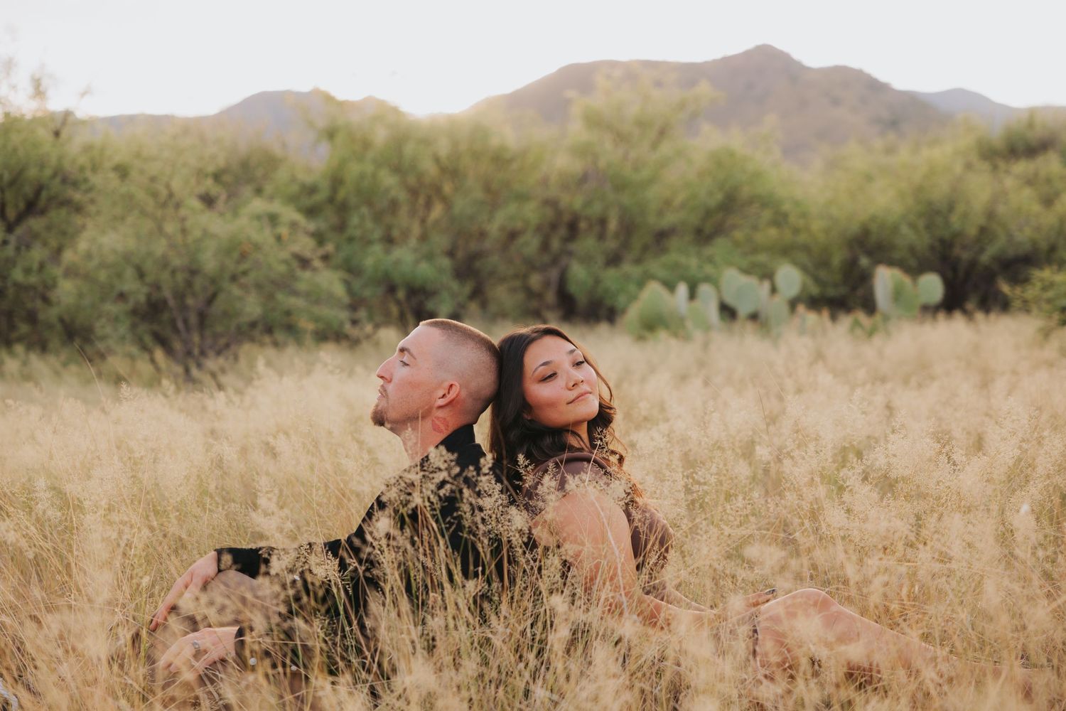 A desert maternity photoshoot featuring flowing dresses and golden light among mountains and cacti.