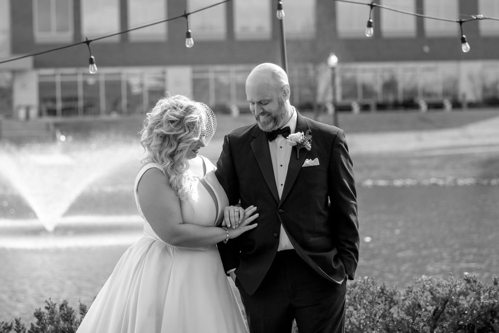 Wedding couple poses outdoors with string lights in the background.