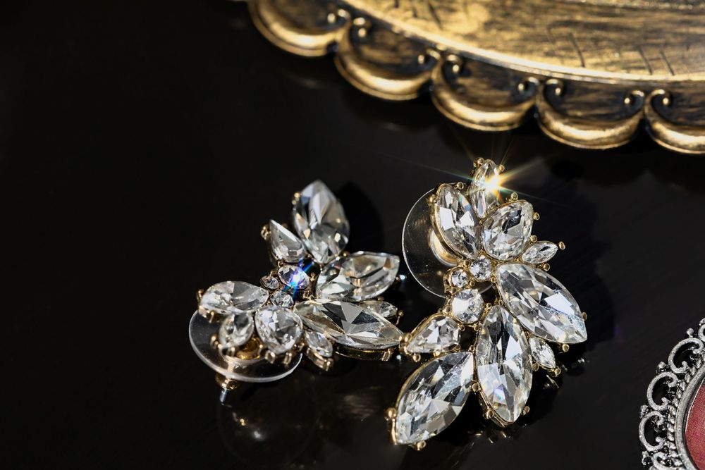 Sparkling bridal jewelry and accessories arranged on dark surface with dramatic lighting.
