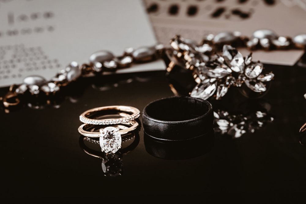 Wedding rings and crystal accessories arranged artistically on dark surface.