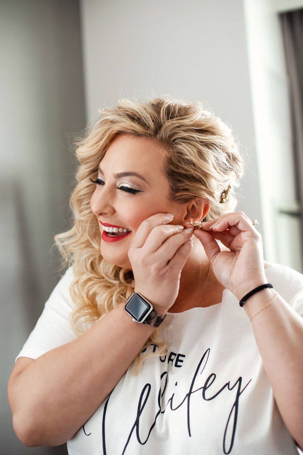 Close-up shots of someone putting on earrings while getting ready in natural window light.