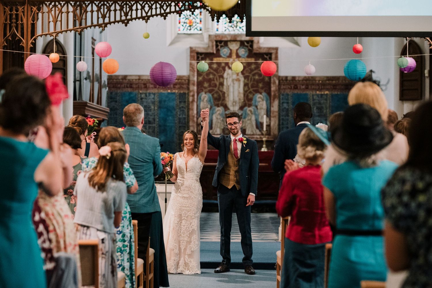 Wedding ceremony in a grand church with colorful balloons and decorative lighting.