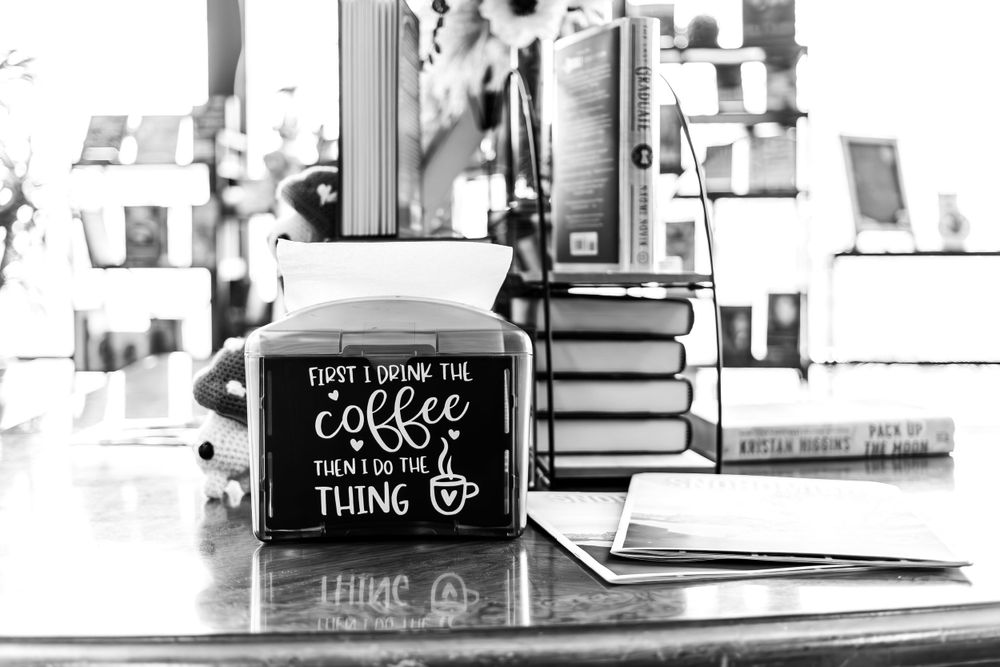 Black and white photo of coffee sign and stacked books.