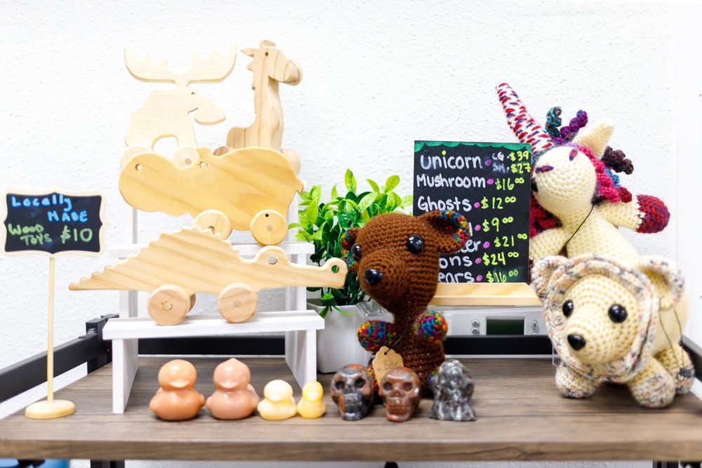 Retail display with wooden toys, plush animals, and small chalkboard signs.
