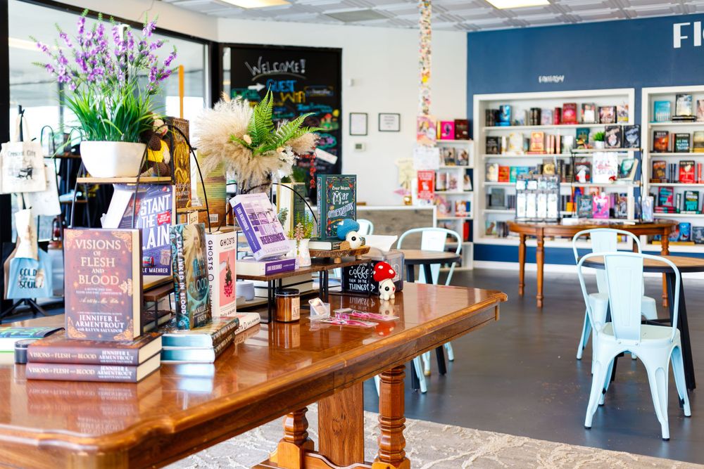 Modern bookstore cafe interior with wooden tables and colorful book displays.