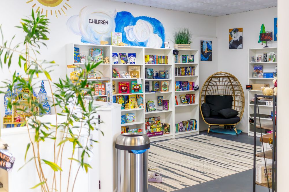 Bright bookstore interior with hanging chair, bookshelves, and potted plants.