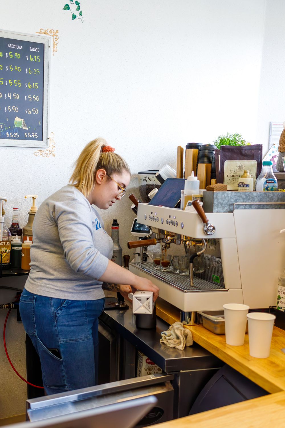 Barista operating an espresso machine in a cafe setting.