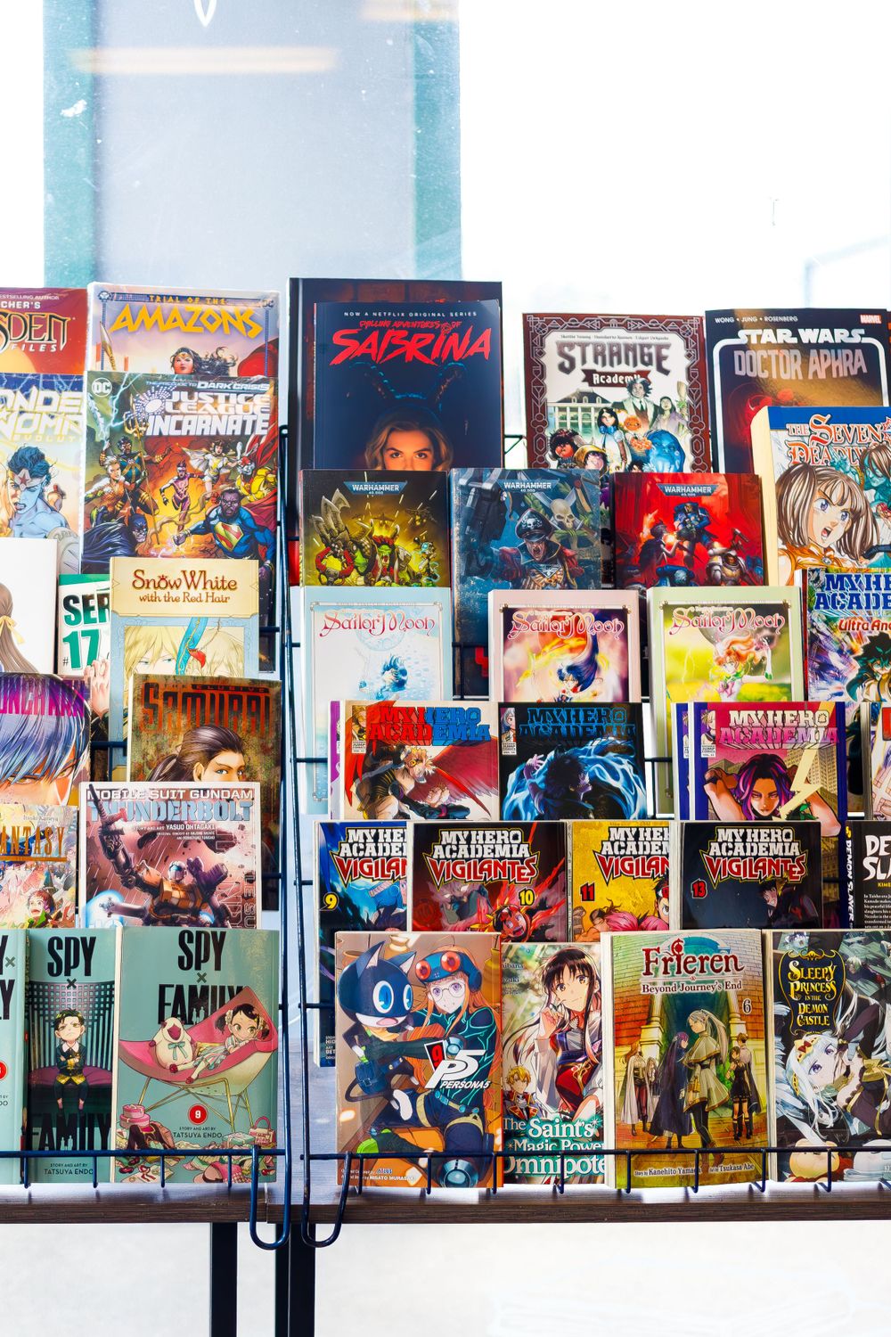 Collection of manga and graphic novels displayed on multiple shelves in a bookstore.