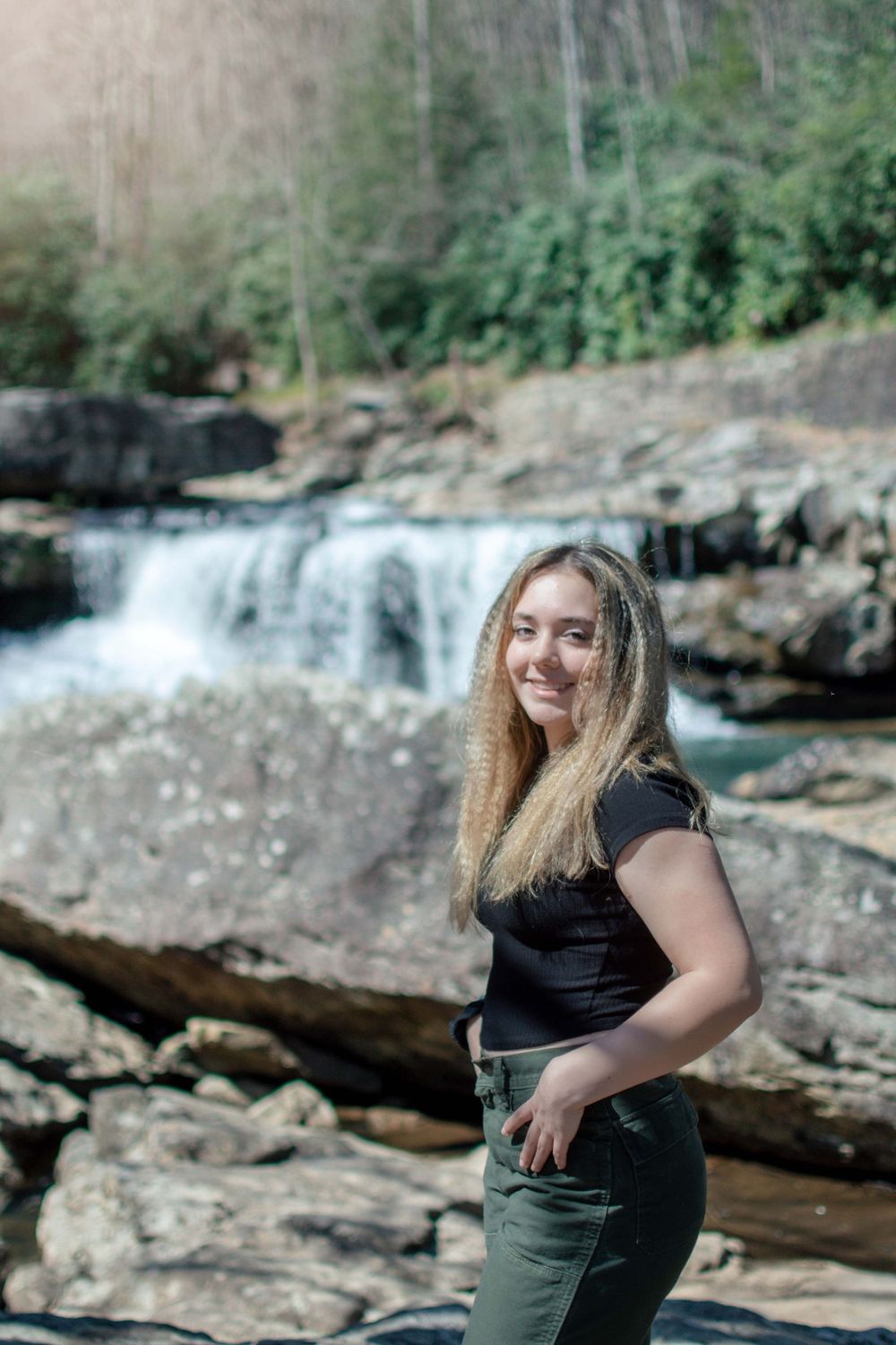 Portrait session at scenic waterfall location with rocks and flowing water in background.
