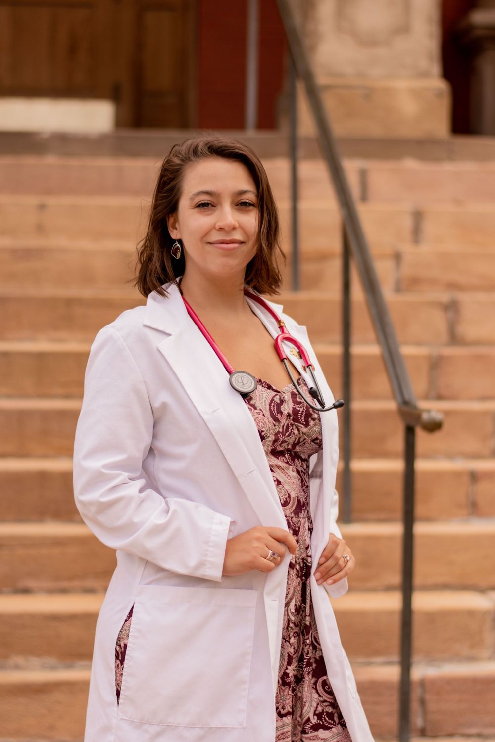 Professional graduation portraits on stone steps featuring a white coat and patterned dress.