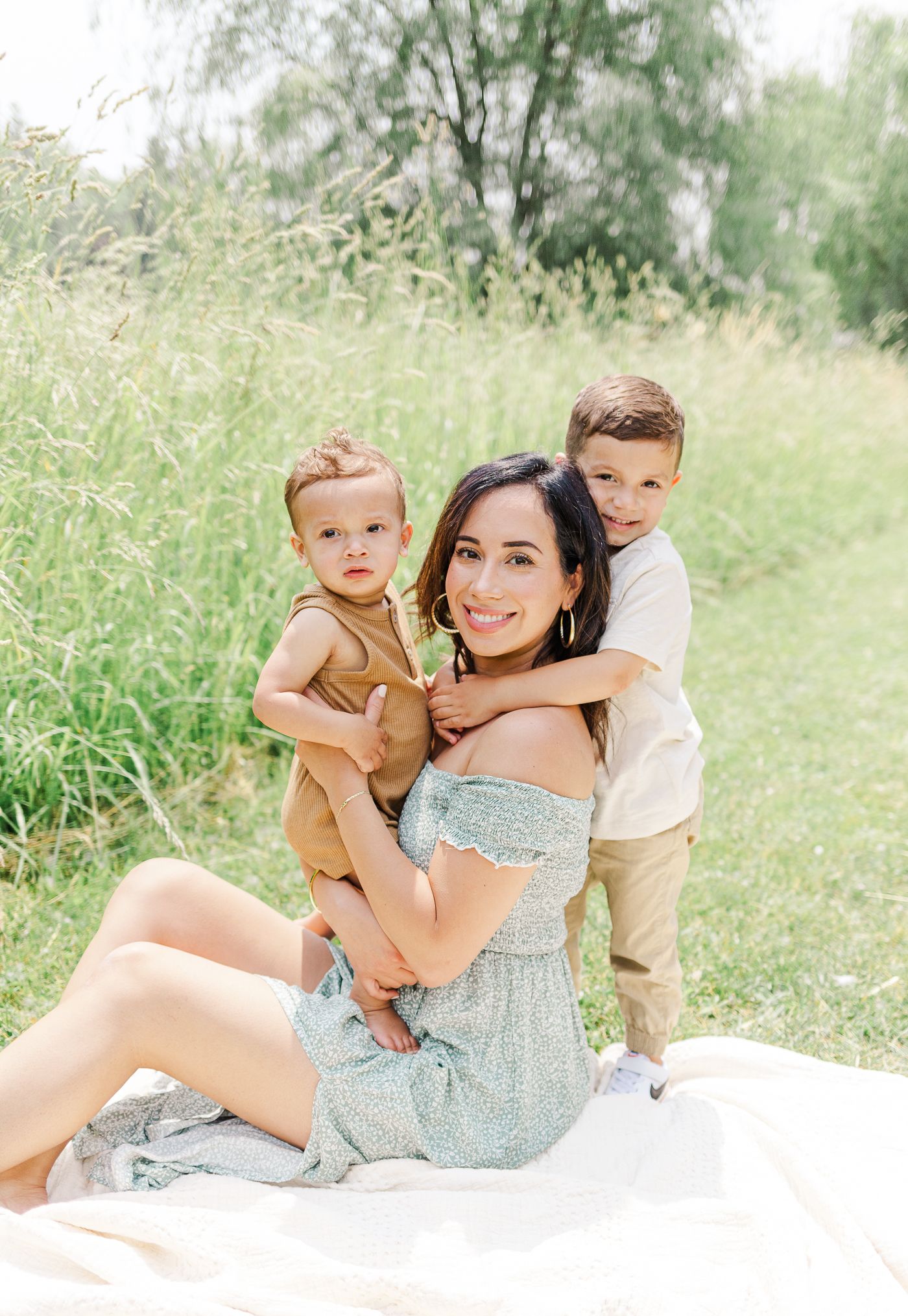Mother and her two boys hugging each other and smiling while sitting on blanket during a Hudson Valley family session
