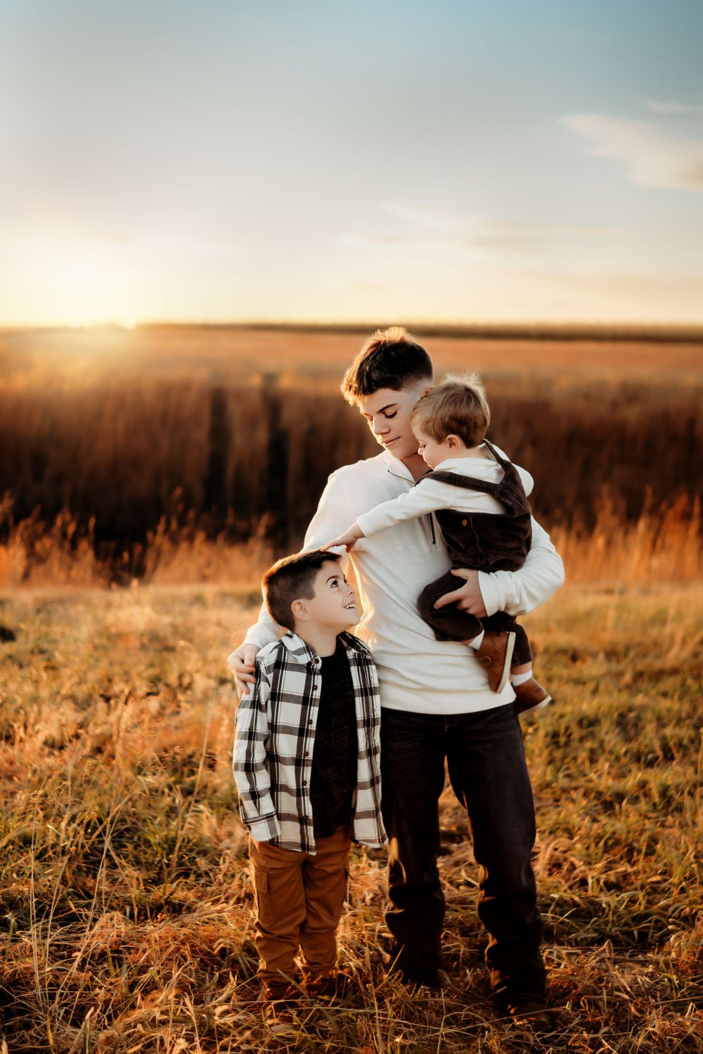 A heartwarming family portrait captured at golden hour in a rustic field setting.