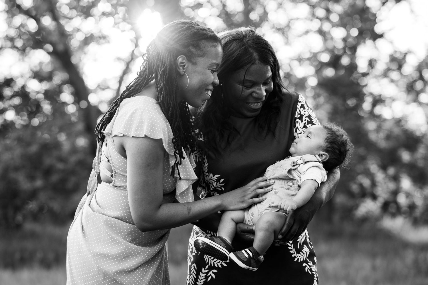 A black and white photo capturing tender family moments with a baby outdoors.