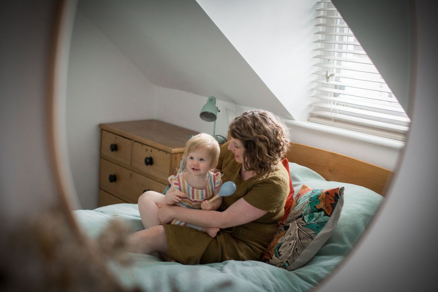mother and small child sitting in bed together playing and laughing
