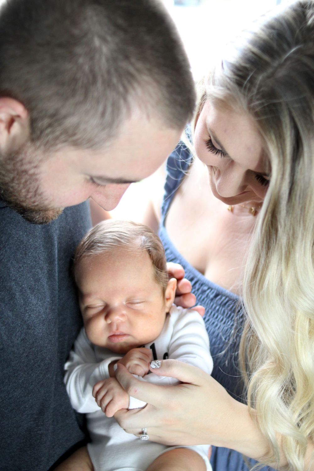 A tender moment with a sleeping newborn being cradled gently.