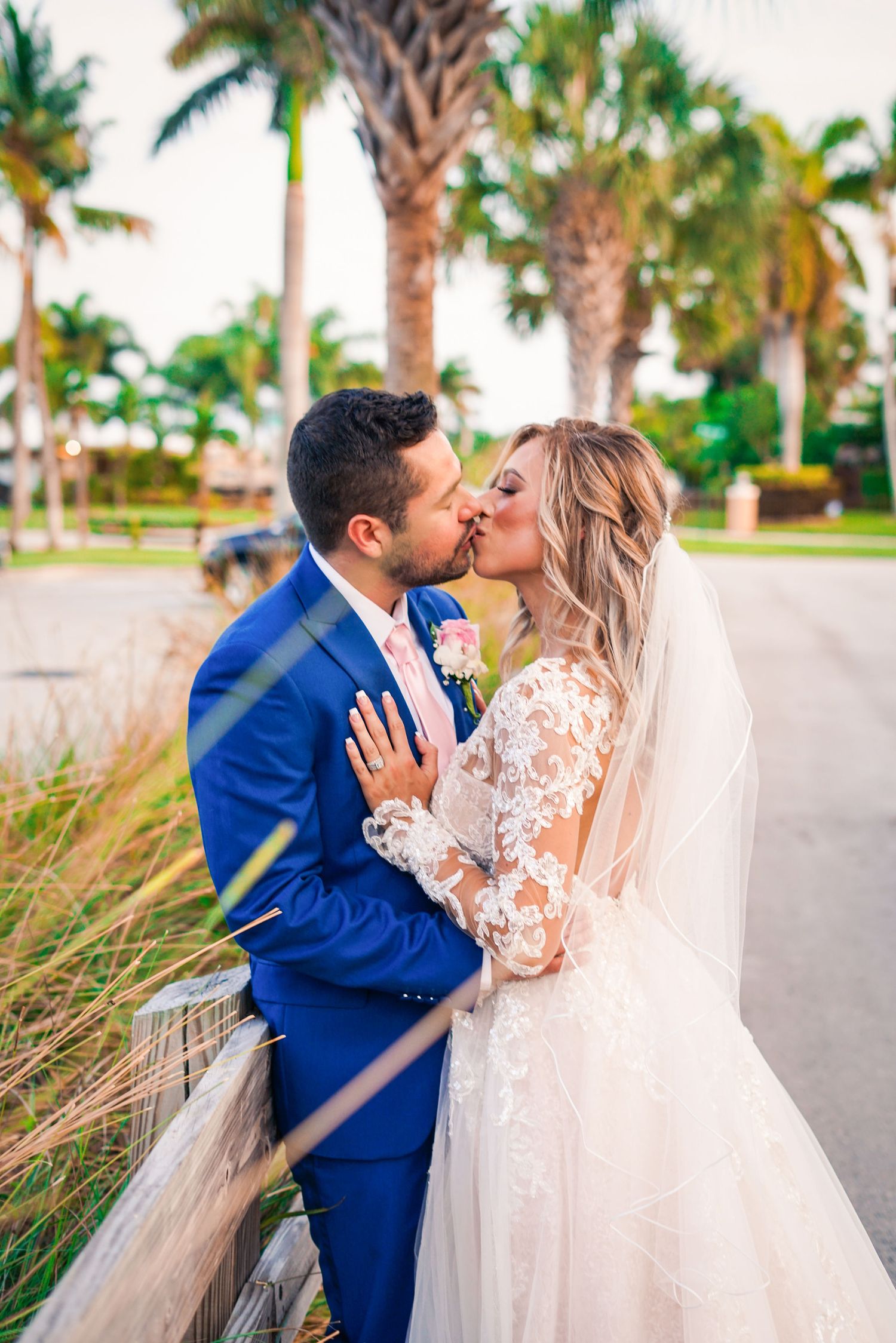 a bride and groom kissing with palm trees in the foreground and background