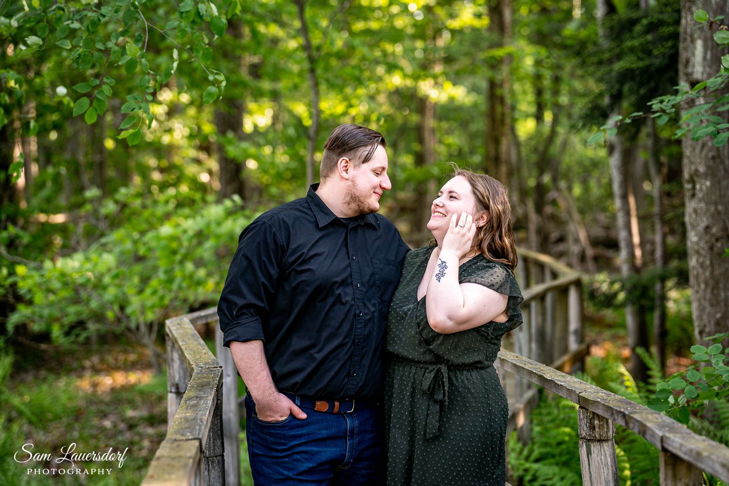 A joyful outdoor portrait on a wooden bridge surrounded by forest greenery. couples photography in wisconsin