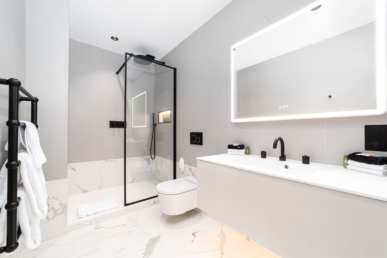 Modern white bathroom with black-framed glass shower, LED mirror and freestanding bathtub, bathroom interior photography