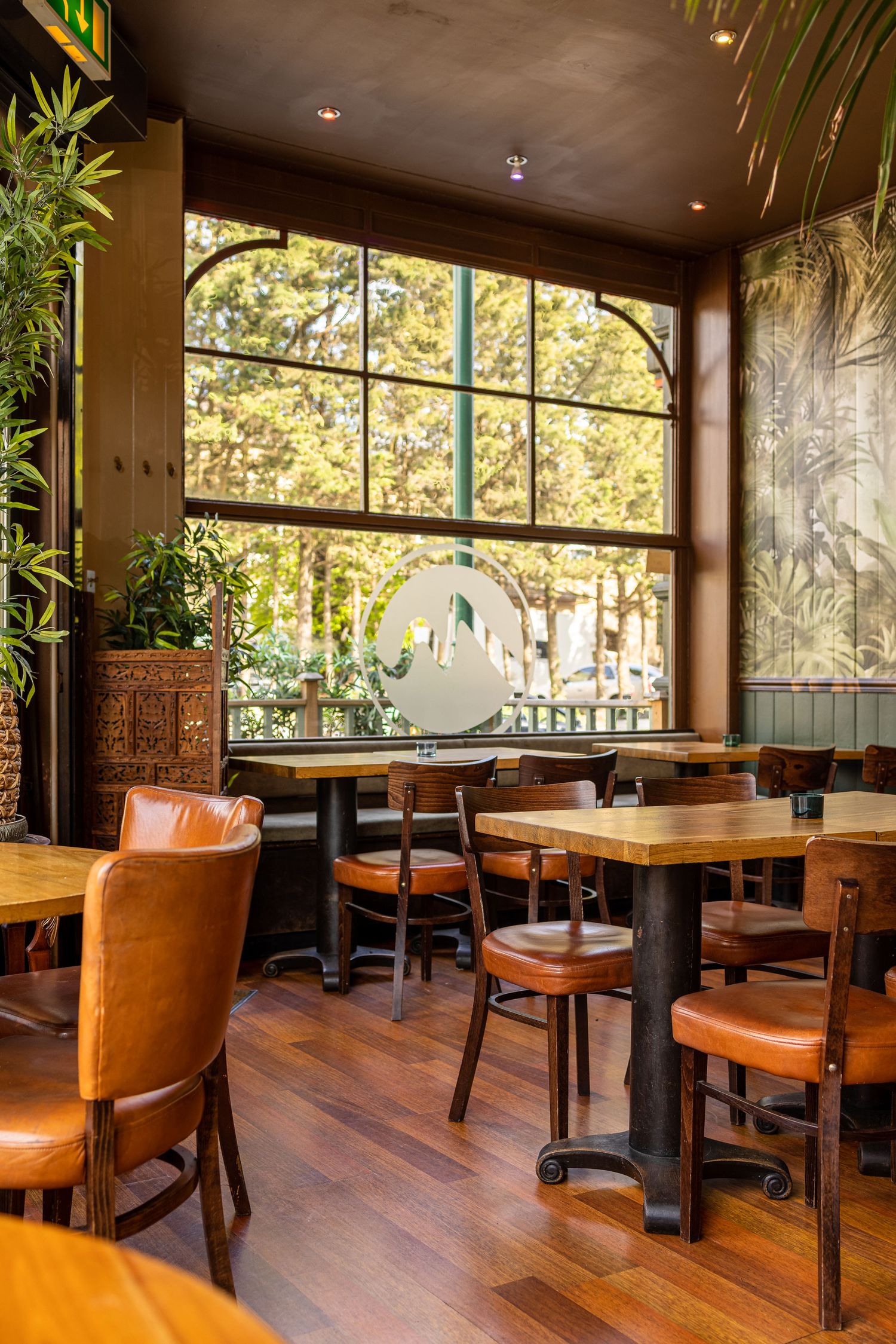Restaurant interior with arched windows, wooden floors, leather chairs and pendant lighting, commercial interior photography