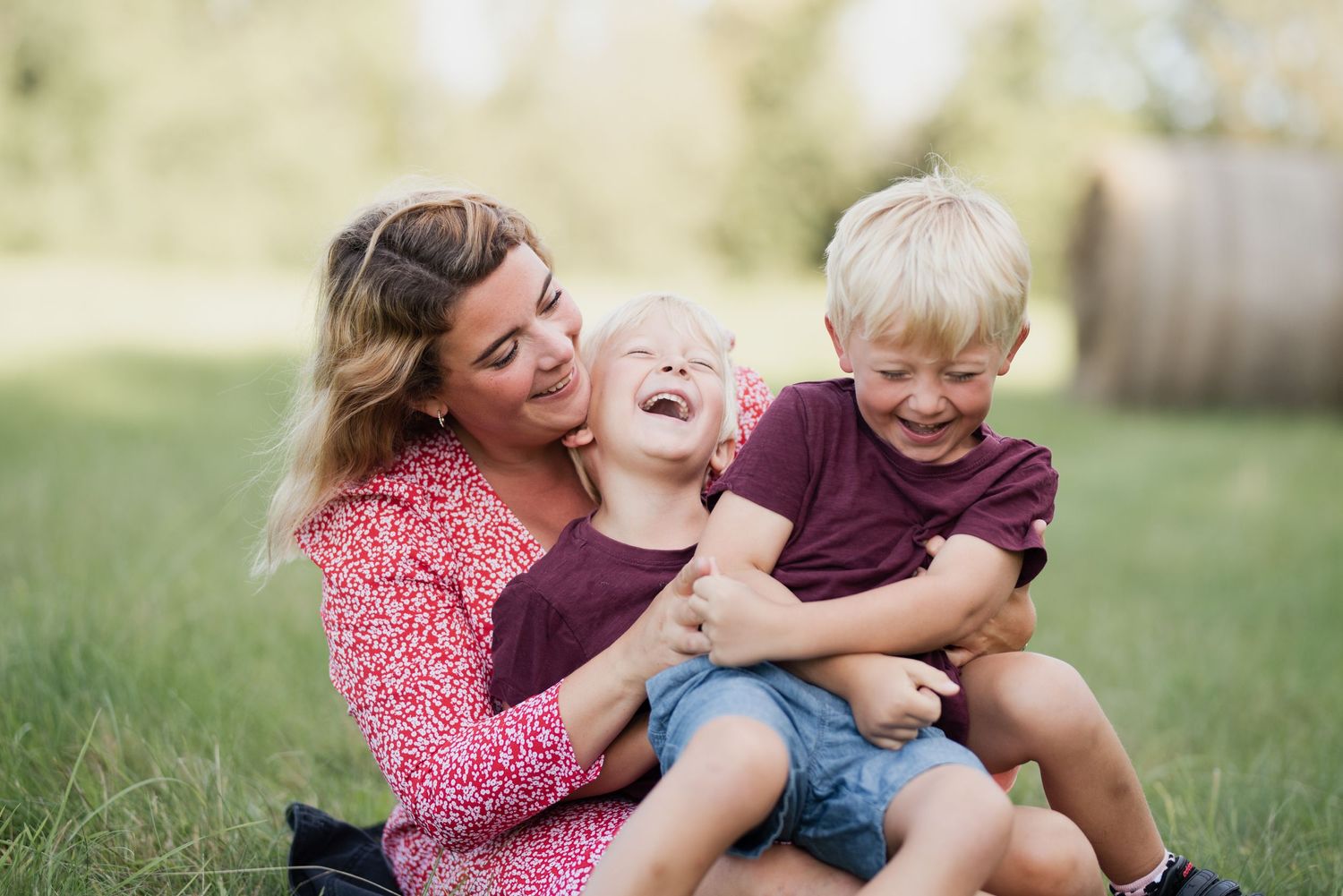 A joyful outdoor family moment captured with playful laughter and embraces on a sunny day.