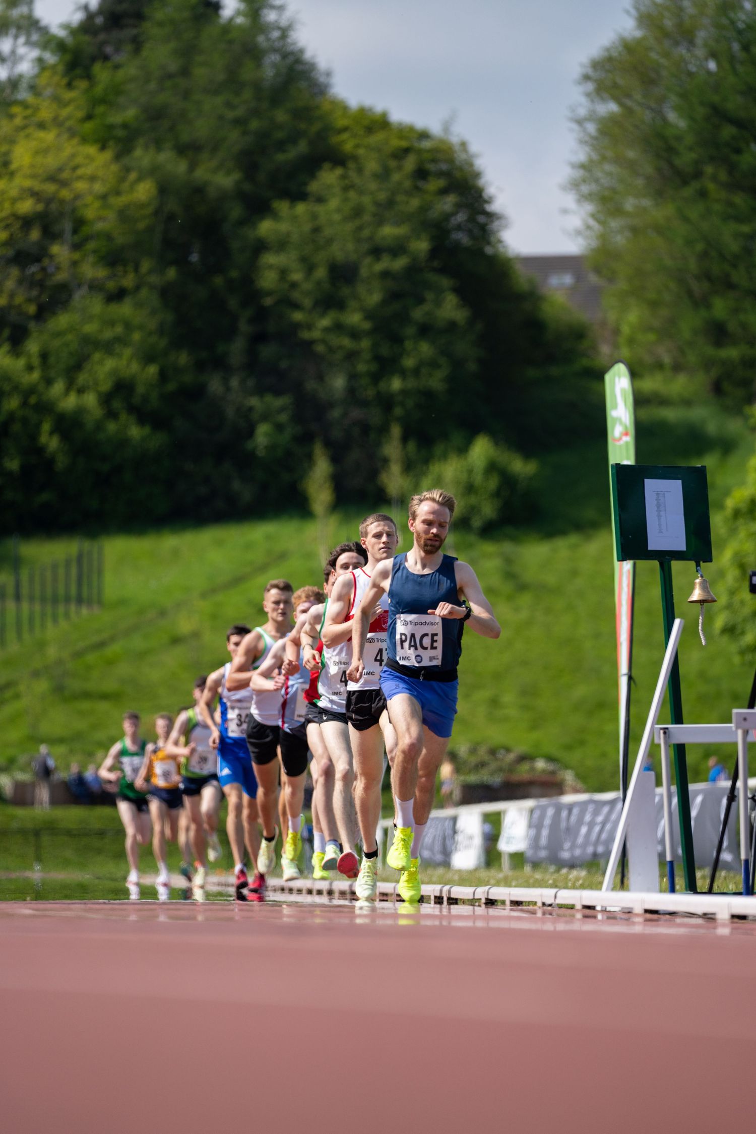 Group of runners competing in a track race on an outdoor athletics track.