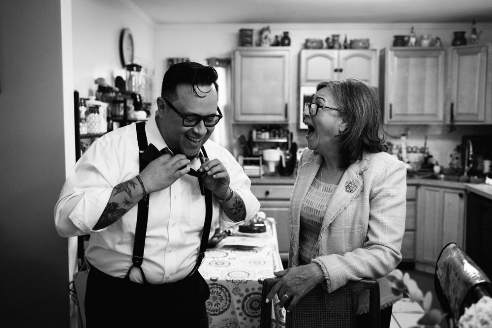 Mother of the groom laughs as her son tries to tie his real bowtie on the morning of his NYC City Hall Wedding.