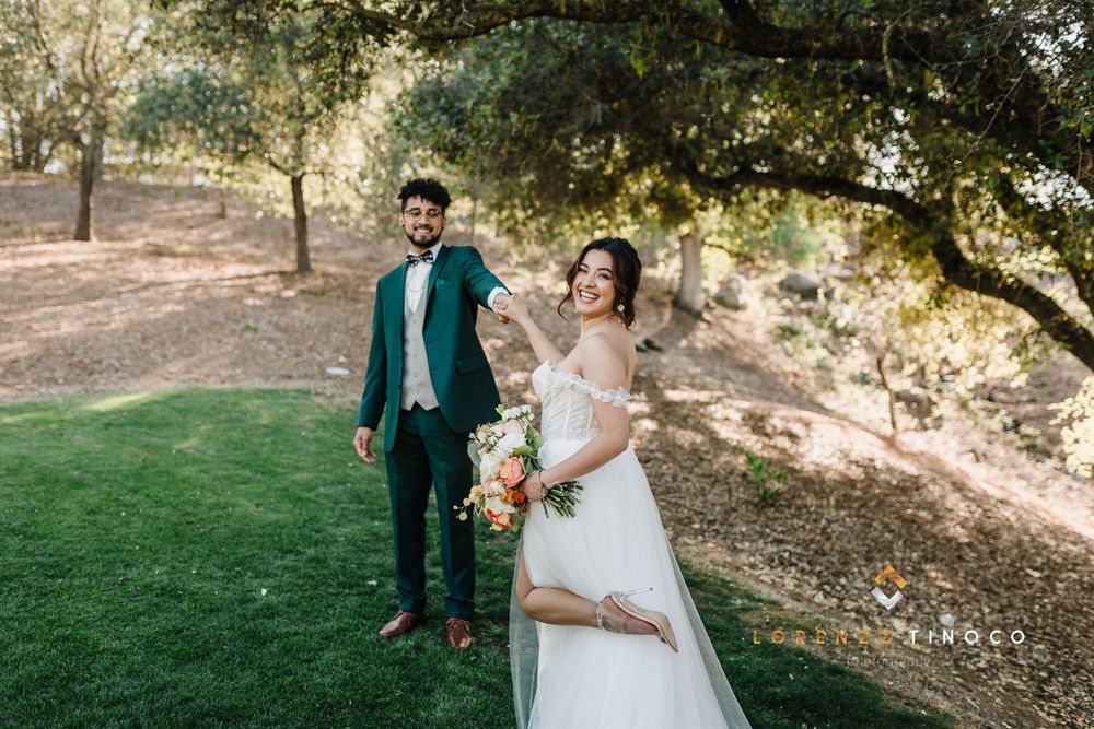 A joyful outdoor wedding photo on a grassy lawn with trees in the background.