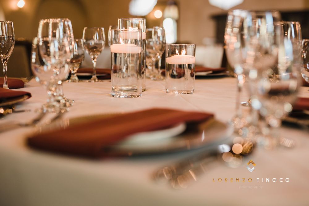 Elegant place setting at wedding reception with wine glasses and copper accents.