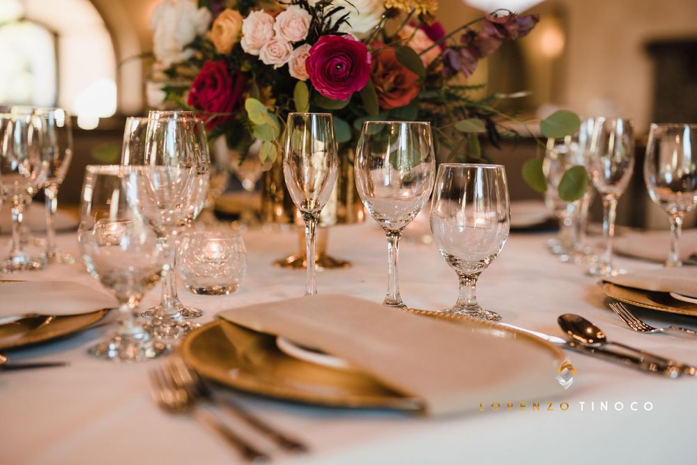 Elegant wedding table setting with pink and red floral centerpiece and crystal stemware.
