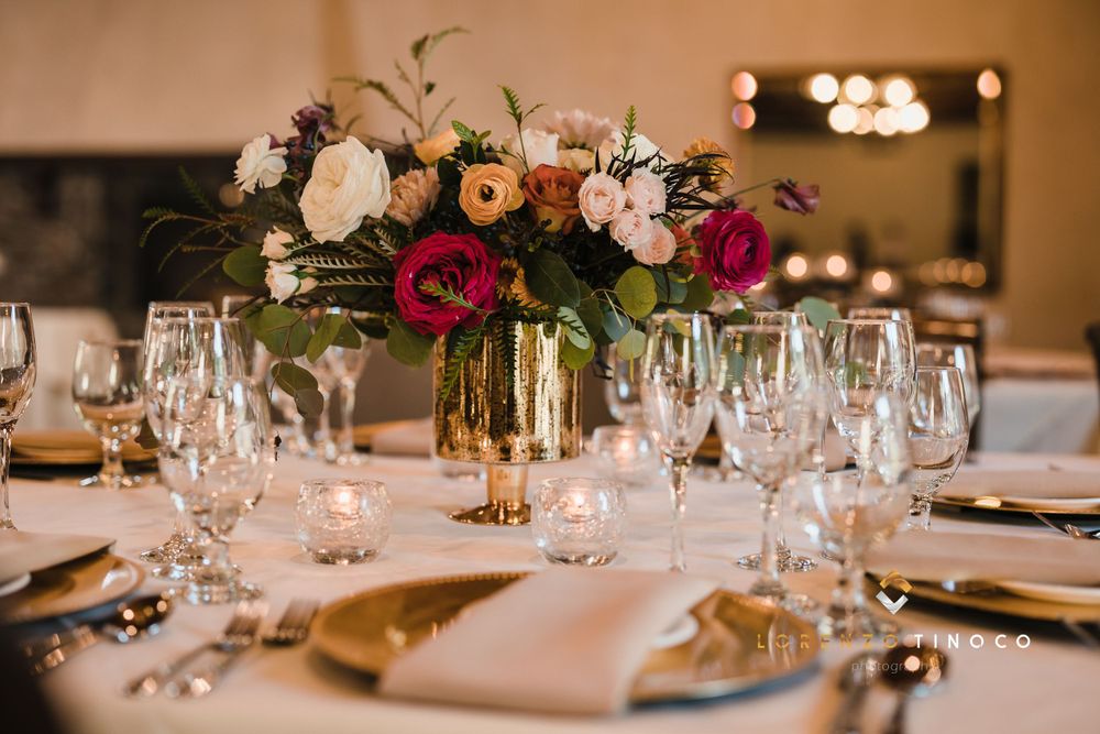 Wedding reception table with luxurious floral centerpiece featuring deep red and blush blooms.