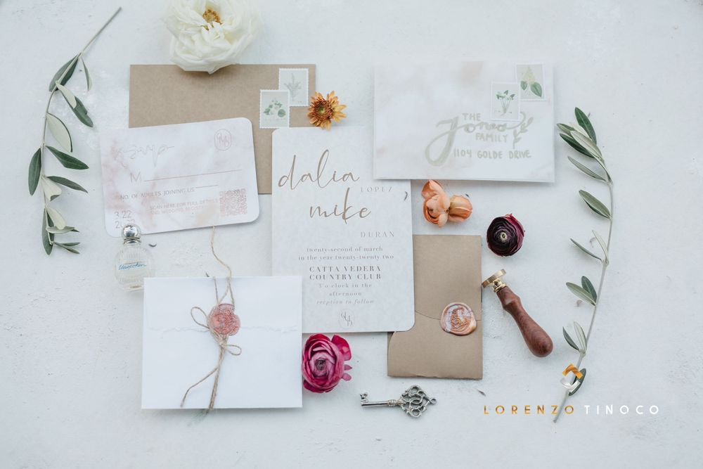 Wedding stationery flat lay with floral elements, wax seals and elegant calligraphy on white background.