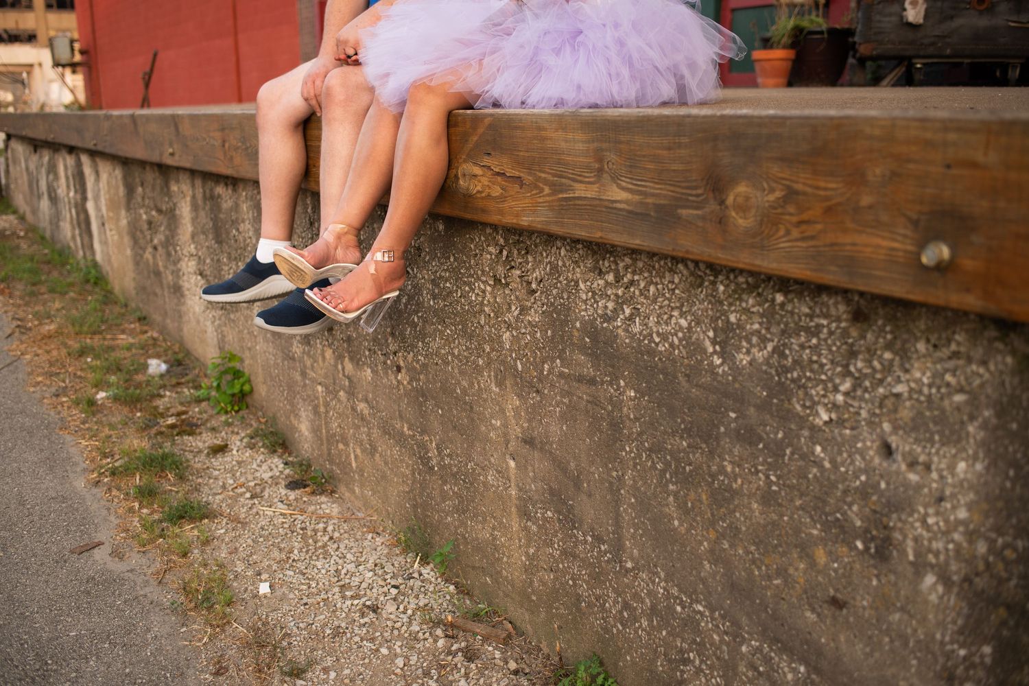 Casual feet dangling over a concrete wall showing coordinated blue sneakers.