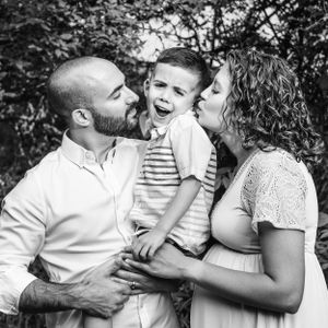 boy with cute face getting kissed by parents
