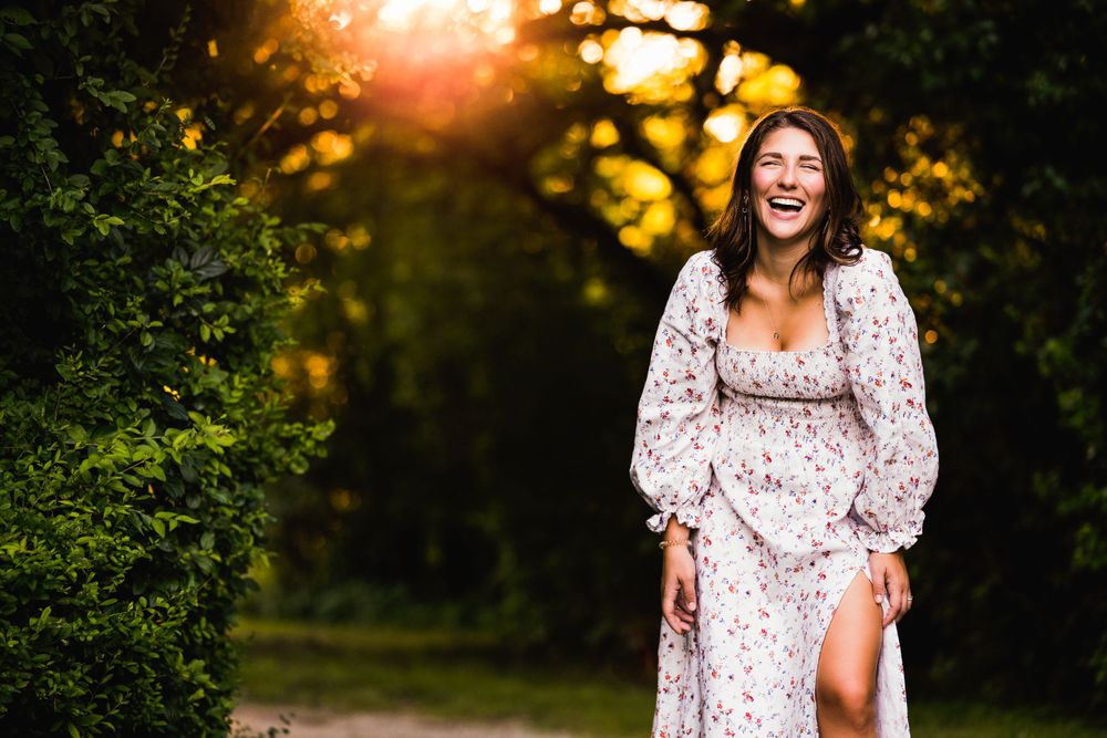 young woman in sundress laughing at sunset