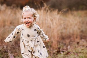 Fall photo of young girl running through tall grasses