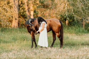 Future mom to be in a white dress shares a moment with her horse in Houston.