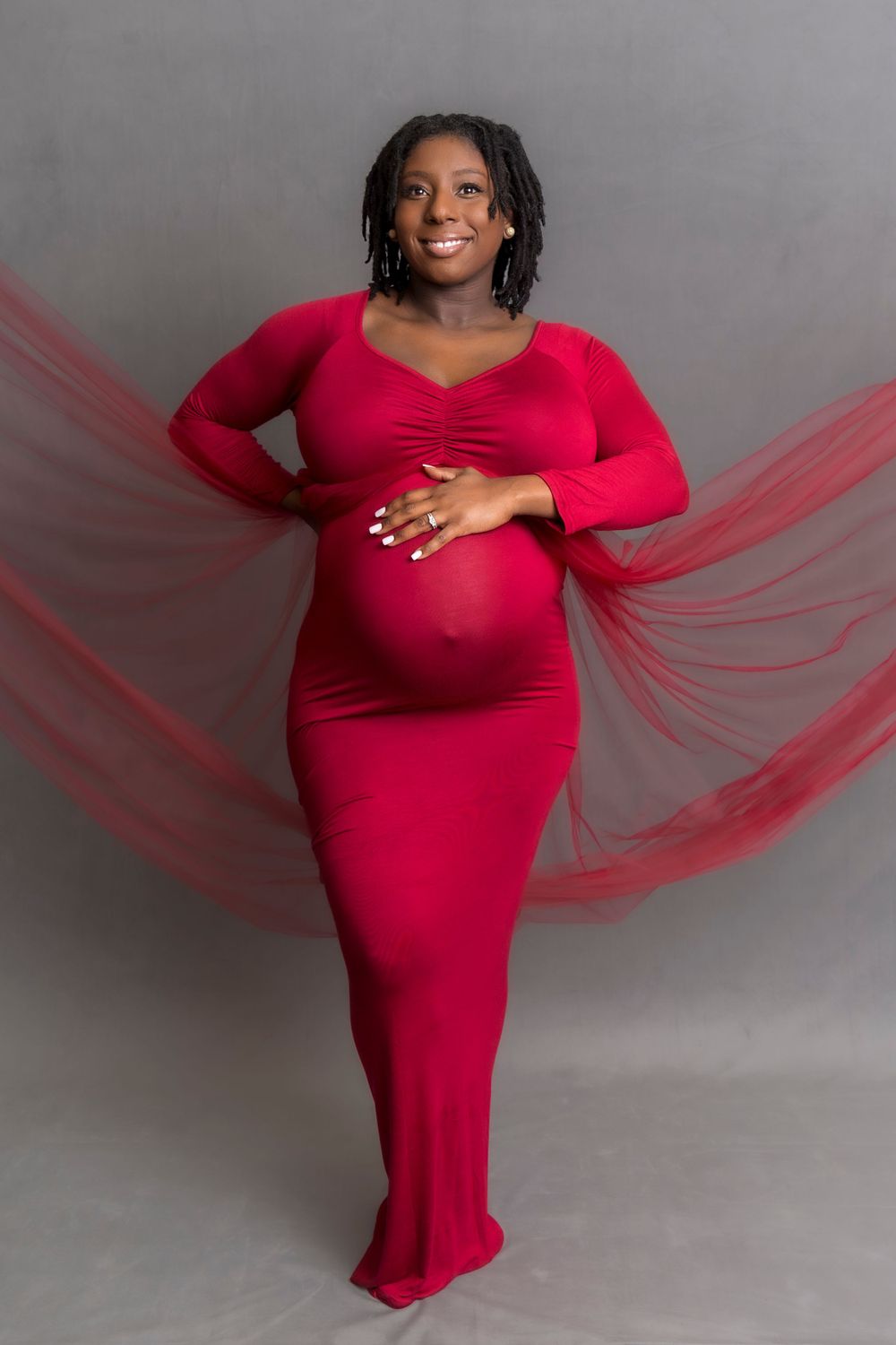 Mom to be poses with a red dress