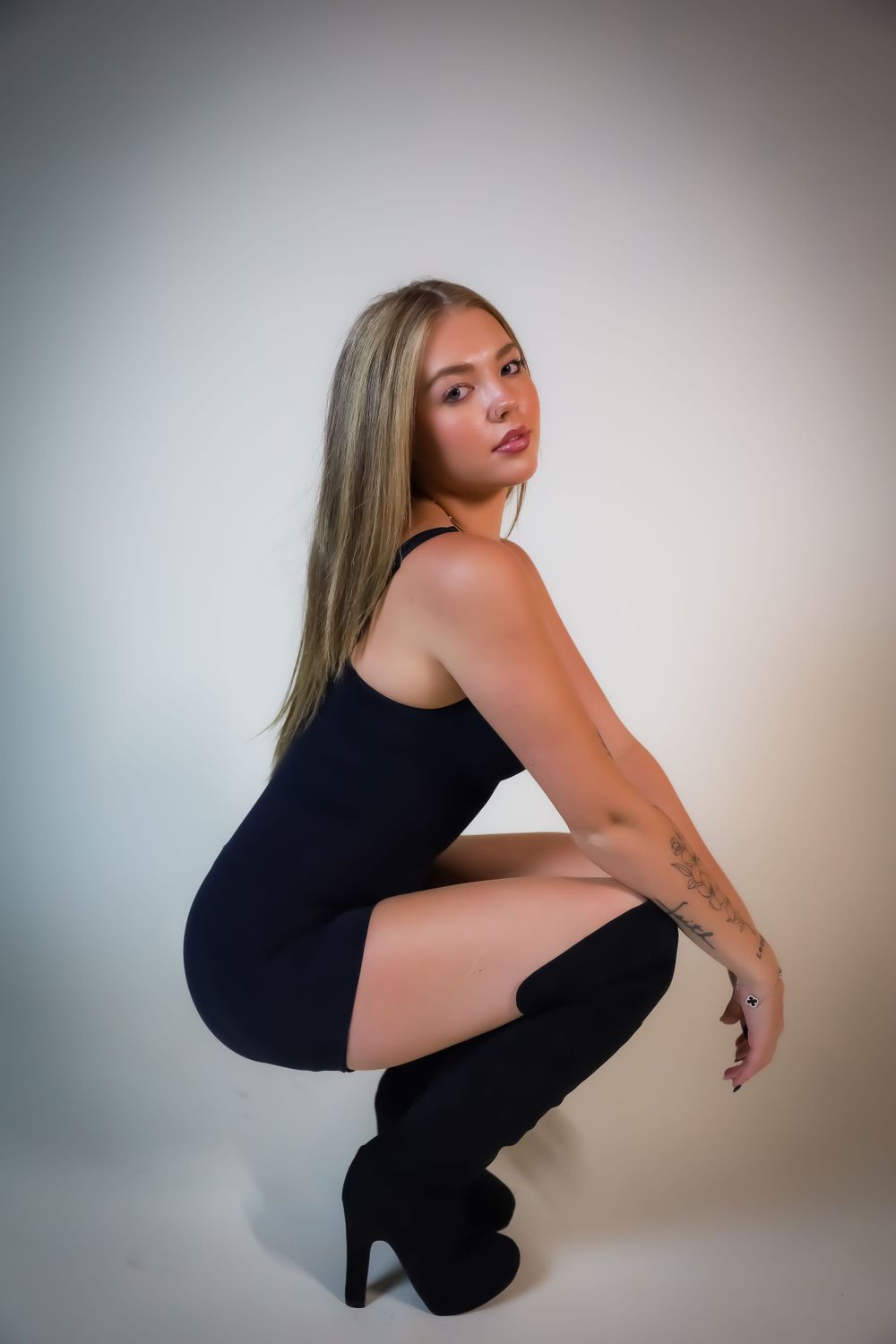 A figure in a black bodysuit poses gracefully against a light background in a series of artistic portrait shots.