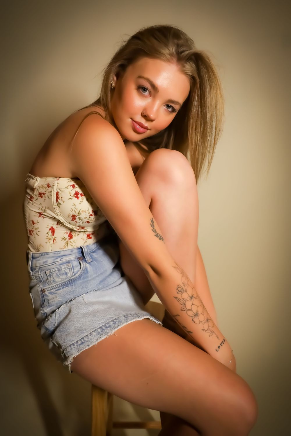 Artistic portrait featuring floral top and denim shorts in warm lighting.