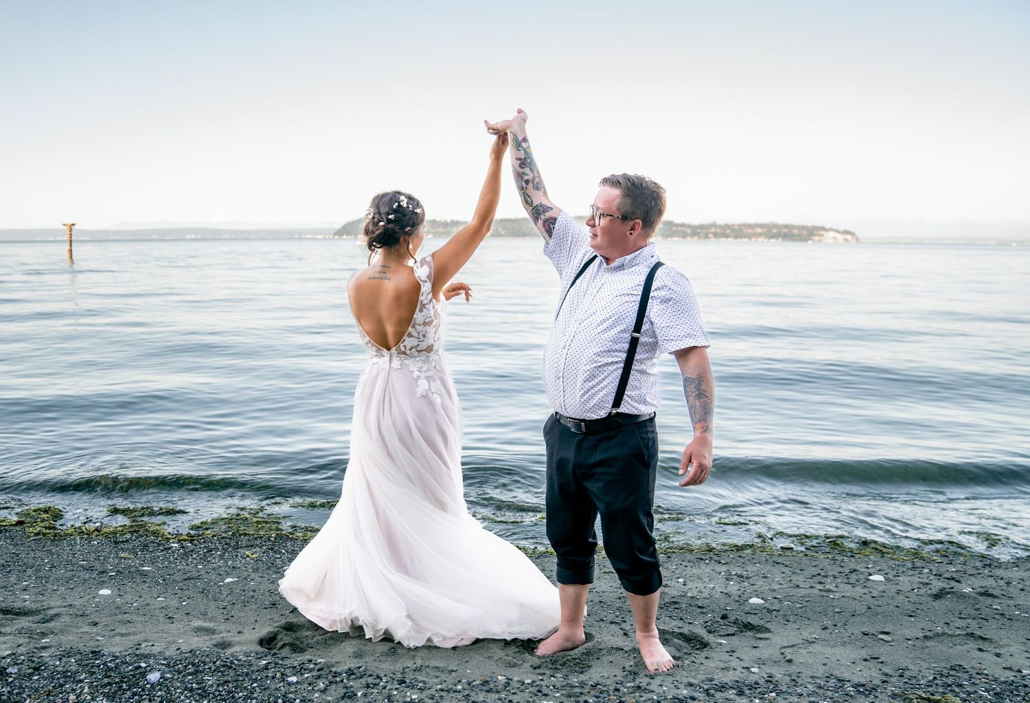 Couple dancing together on beach shore with ocean waves in background.
